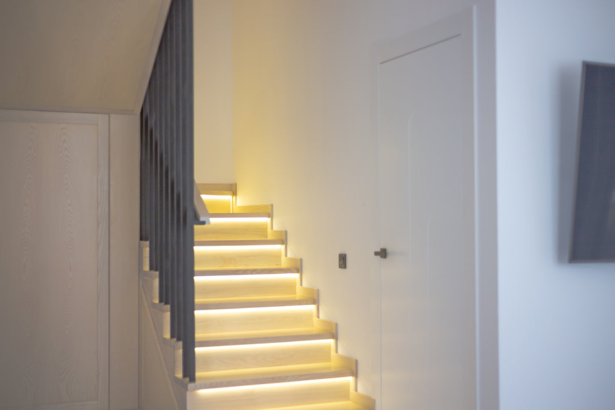 A white staircase with a light on the side of it