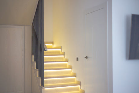 A white staircase with a light on the side of it