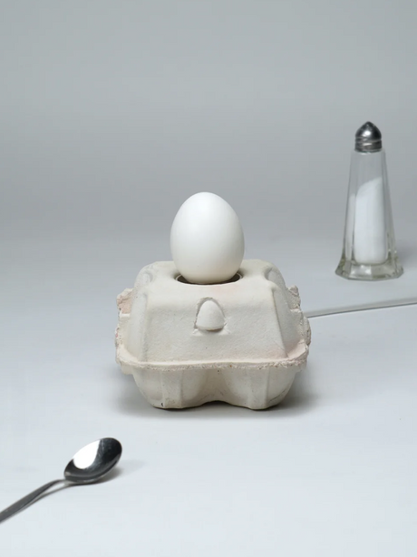 EggboxLAMP Classic LED lamp in ei-vorm, geplaatst op een kartonnen eierdoos met witte ei