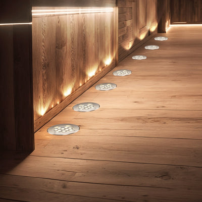 LED grondspots warmwit ingebouwd in een houten vlonder langs een schutting